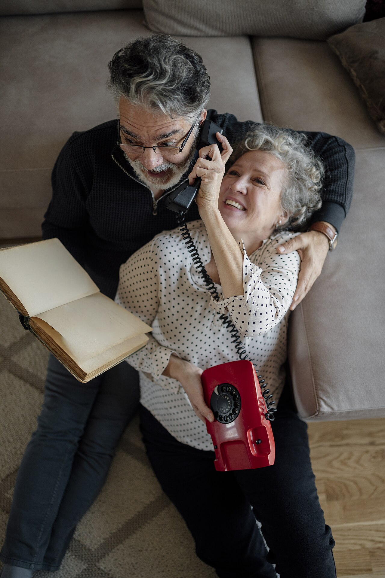 Couple sitting apart on a couch while one person holds a phone